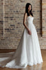 Woman in a white wedding dress standing against a brick wall.
