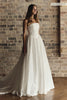 A woman modeling a strapless white A-line wedding gown with a fitted bodice and full skirt