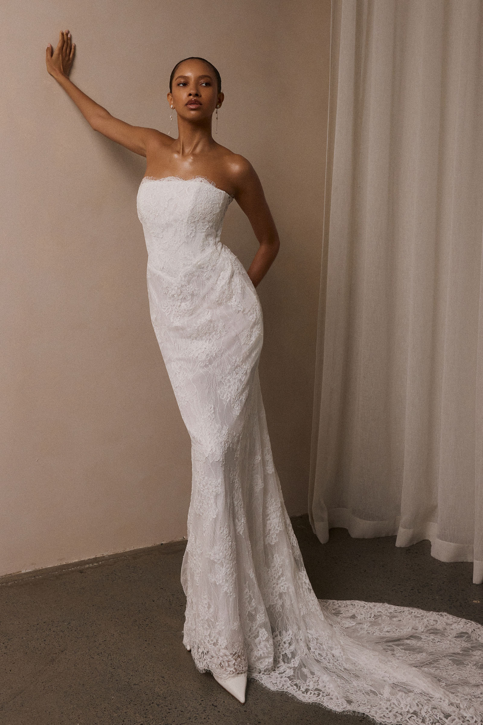 A woman wearing a strapless white lace wedding gown with a long train_XS_