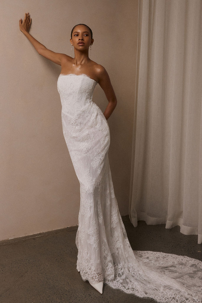 A woman wearing a strapless white lace wedding gown with a long train_XS_