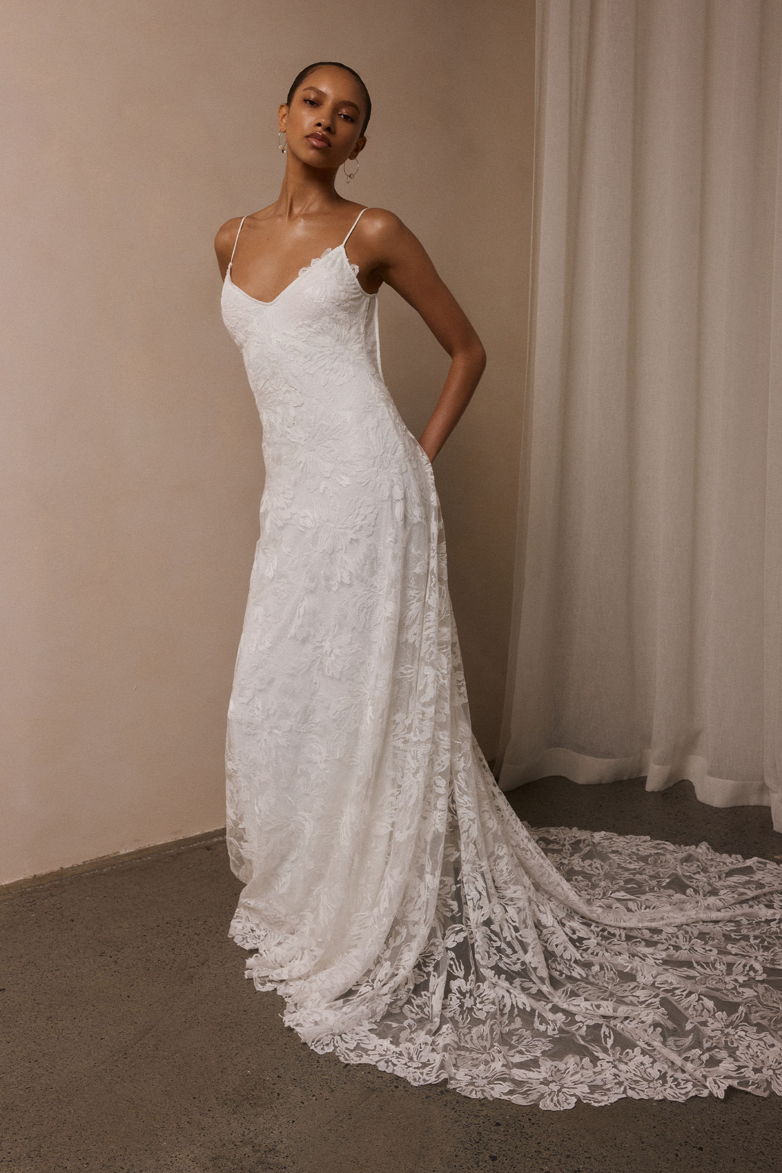 woman wearing a white lace backless dress with thin straps and delicate chain jewellery across her back_XS_