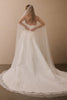 A woman wearing a strapless white wedding gown and a long sheer bridal veil, photographed from behind against a plain beige wall_XS_