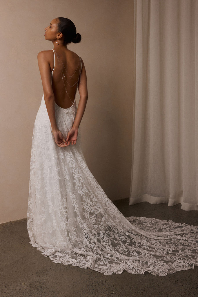 woman wearing a white lace backless dress with thin straps and delicate chain jewellery across her back_XS_