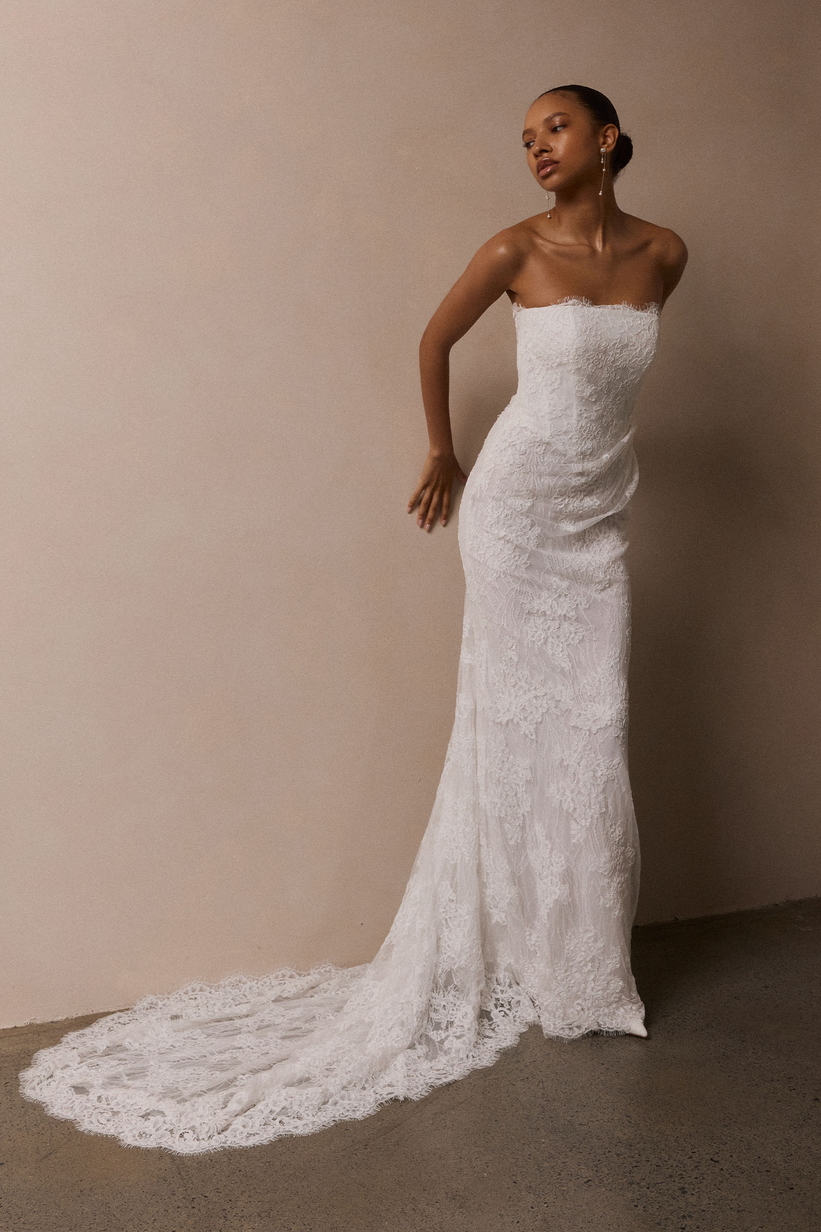 A woman wearing a strapless white lace wedding gown with a long train_XS_