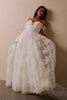 A woman wearing a white off-the-shoulder lace wedding gown with a deep V neckline and a full layered skirt_L_