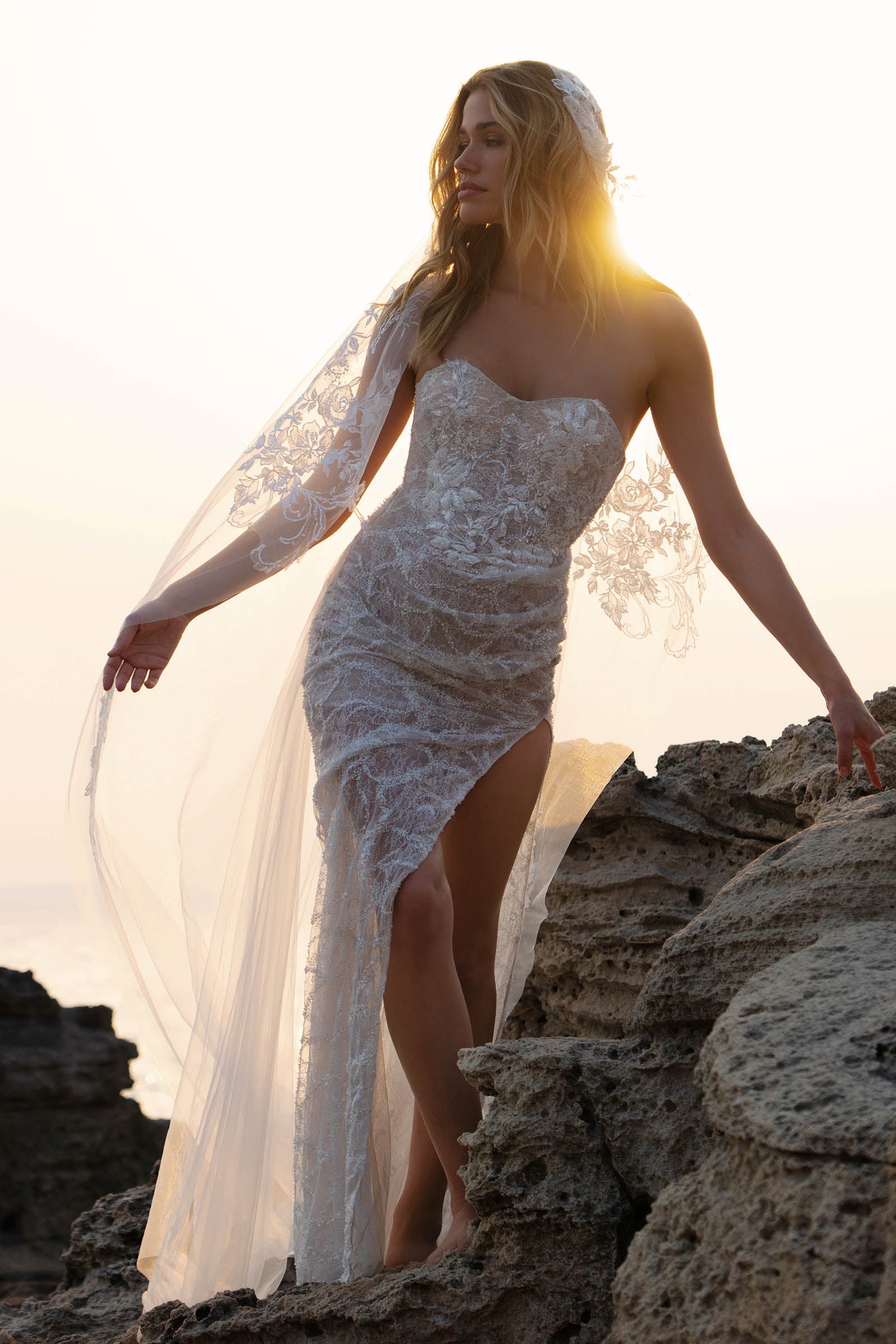 Woman in a strapless lace wedding dress standing on rocks_XS_