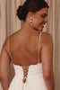 Woman wearing a white dress with thin straps and lace-up back with pearl earrings