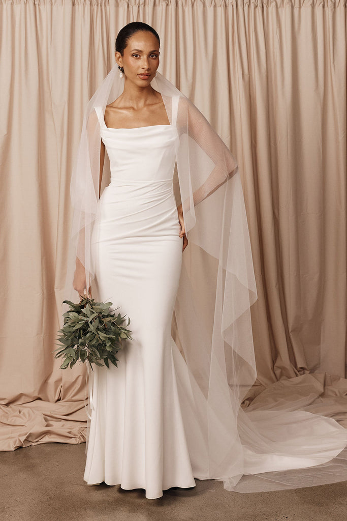 A bride wearing a crepe wedding dress and tulle drop veil