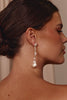 Close-up of a woman wearing pearl earrings with a neutral background