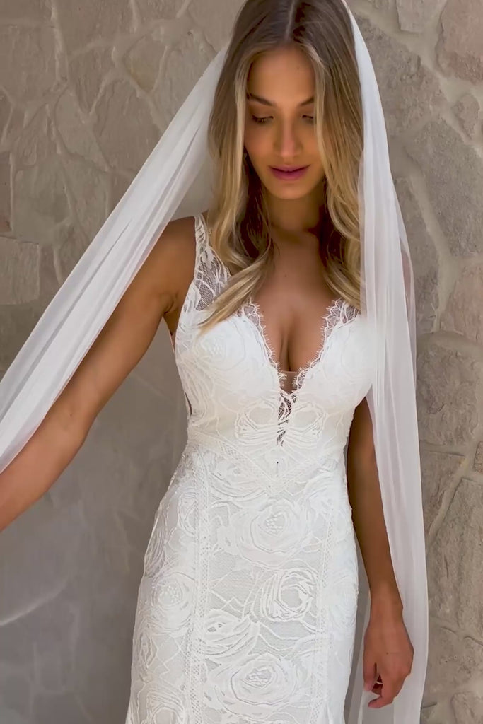 A woman wearing a V-neck lace wedding dress and veil.