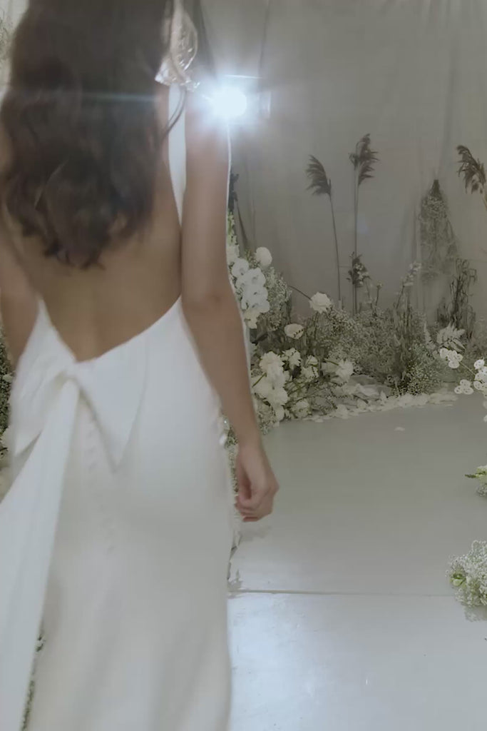 A woman wearing a low back crepe wedding dress.